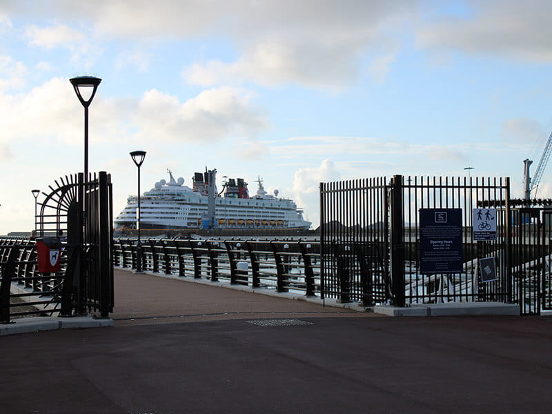 Double leaf vertical bar security gates at entrance to pier with ferry behind